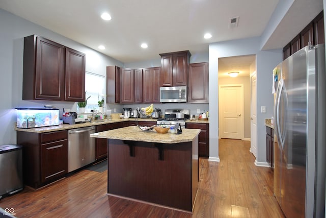 kitchen with a kitchen island, appliances with stainless steel finishes, dark hardwood / wood-style floors, sink, and a kitchen breakfast bar