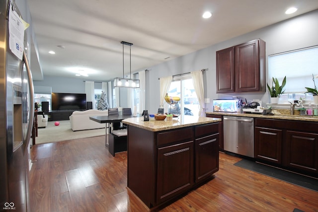 kitchen featuring sink, appliances with stainless steel finishes, hanging light fixtures, dark hardwood / wood-style floors, and a kitchen island