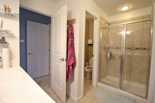 bathroom with walk in shower, vanity, tile patterned floors, and toilet