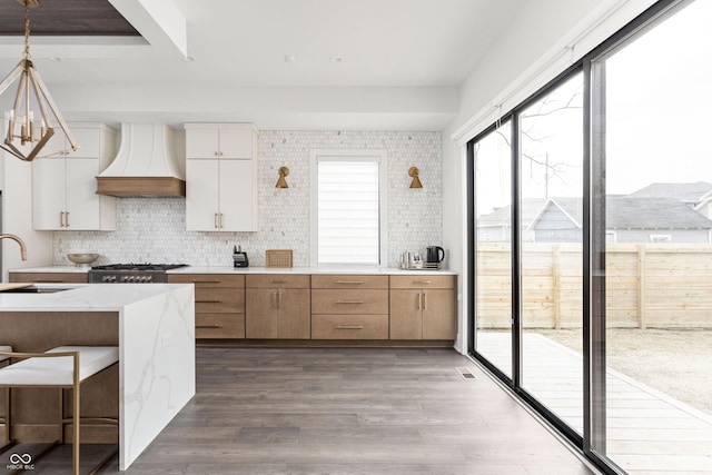 kitchen with pendant lighting, sink, white cabinets, light hardwood / wood-style floors, and custom range hood