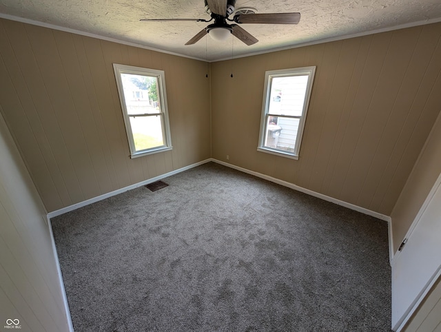 603 W 33rd St, Anderson, IN 46013 - spare room featuring ceiling fan, a textured ceiling, ornamental molding, carpet flooring, and wood walls