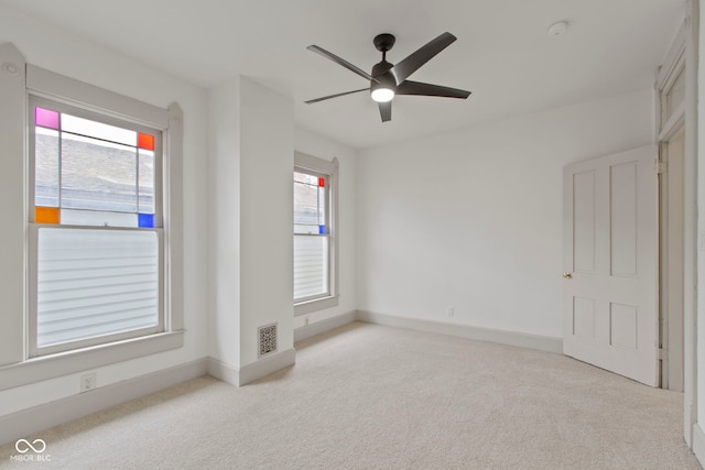 carpeted spare room featuring ceiling fan and a wealth of natural light