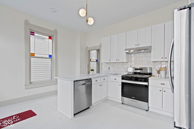 kitchen with hanging light fixtures, appliances with stainless steel finishes, white cabinets, and backsplash