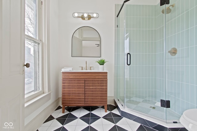 bathroom with tile patterned flooring, vanity, a shower with shower door, and toilet