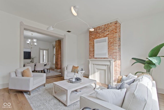 living room with an inviting chandelier, a fireplace, and light hardwood / wood-style flooring