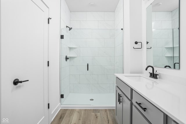 bathroom featuring hardwood / wood-style flooring, vanity, and a shower with door