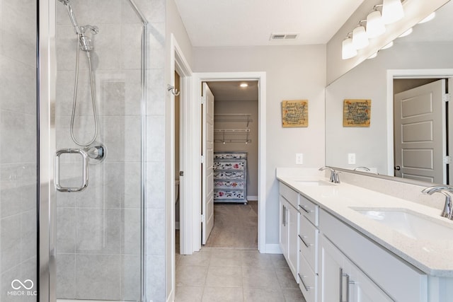 bathroom with a spacious closet, a stall shower, a sink, and visible vents