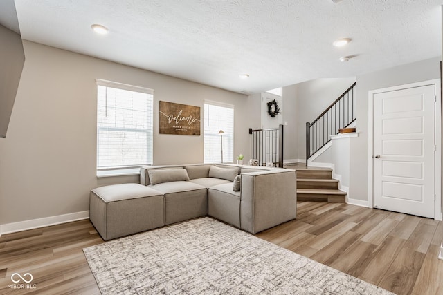 living area featuring light wood finished floors, stairs, and baseboards