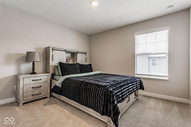 bedroom with light colored carpet, a textured ceiling, and baseboards