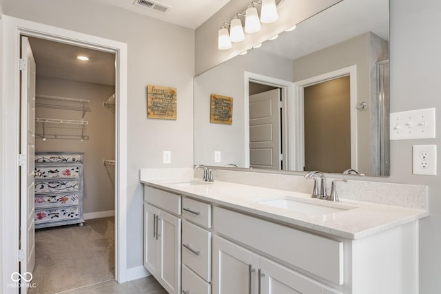 bathroom featuring double vanity, baseboards, visible vents, and a sink