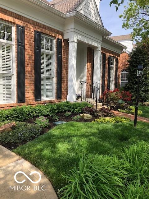 doorway to property featuring brick siding and a lawn