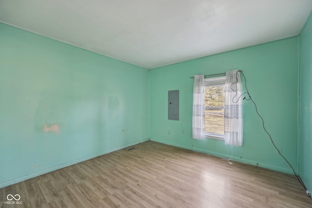 unfurnished room with electric panel and light wood-type flooring