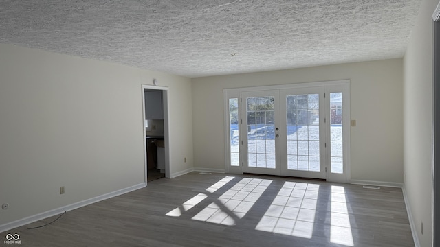 spare room featuring hardwood / wood-style floors, french doors, and a textured ceiling