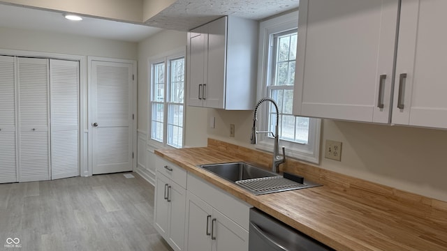 kitchen with wooden counters, sink, white cabinets, and light wood-type flooring