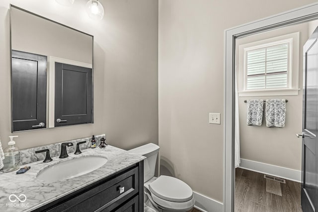 bathroom featuring vanity, wood-type flooring, and toilet