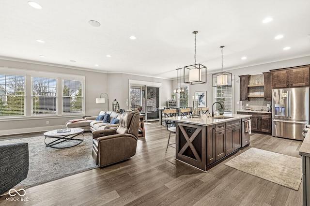 kitchen with appliances with stainless steel finishes, decorative light fixtures, sink, dark brown cabinets, and a center island with sink