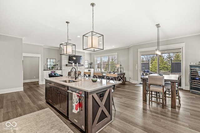 kitchen featuring pendant lighting, dishwasher, sink, dark brown cabinetry, and a center island with sink