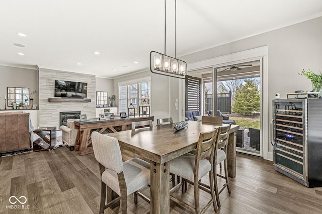 dining room featuring wine cooler, plenty of natural light, crown molding, and a tile fireplace