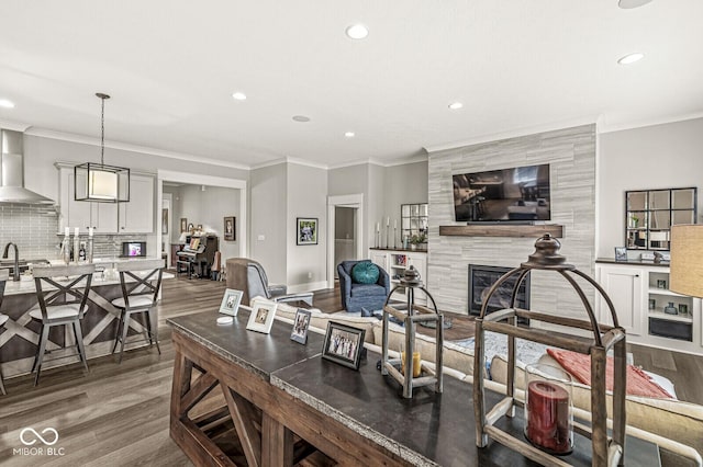 living room featuring crown molding, wood-type flooring, and a tile fireplace