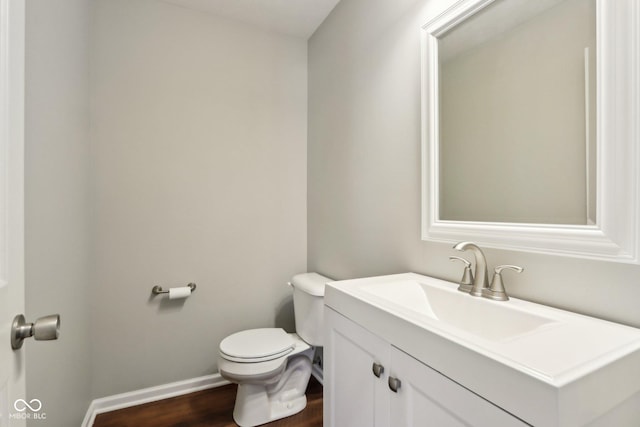 half bath featuring baseboards, toilet, wood finished floors, and vanity