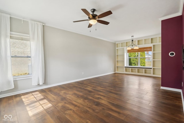 empty room with ornamental molding, a ceiling fan, built in features, dark wood-style floors, and baseboards