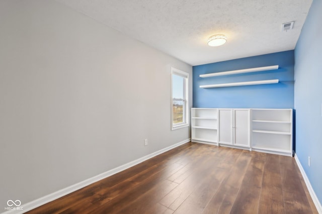 unfurnished bedroom with dark wood finished floors, visible vents, baseboards, and a textured ceiling