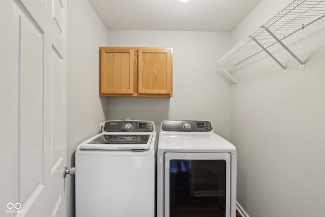 washroom featuring cabinet space, a textured ceiling, and separate washer and dryer