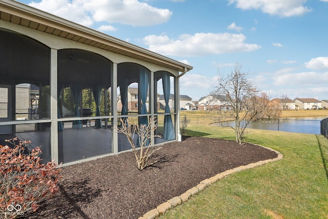 view of side of property featuring a lawn, a water view, and a sunroom