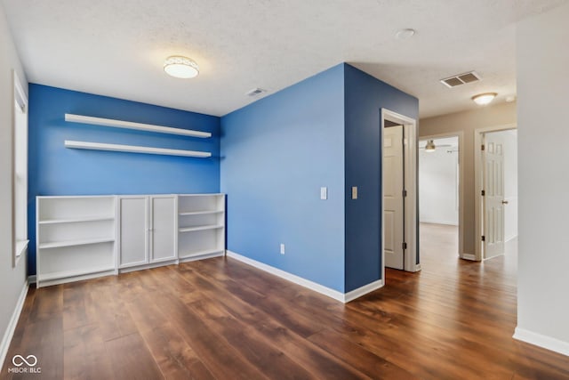 unfurnished bedroom with visible vents, wood finished floors, baseboards, and a textured ceiling