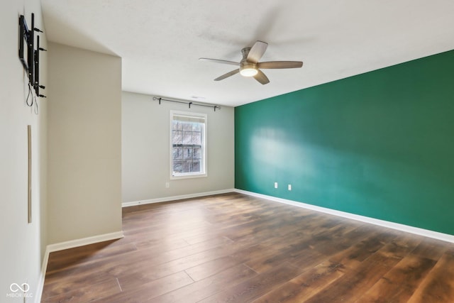 empty room featuring a ceiling fan, baseboards, and wood finished floors