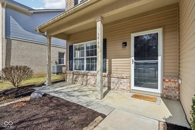 view of exterior entry with cooling unit and brick siding