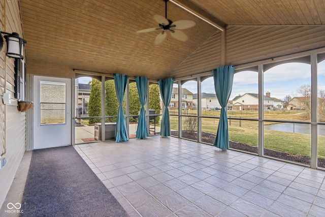 unfurnished sunroom featuring lofted ceiling, ceiling fan, a water view, wooden ceiling, and a residential view