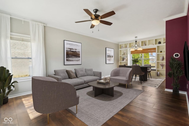 living area featuring built in shelves, dark wood-style floors, baseboards, and ceiling fan