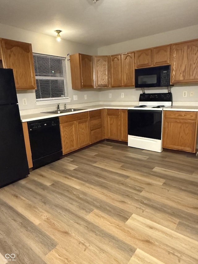 kitchen with sink, light hardwood / wood-style flooring, and black appliances