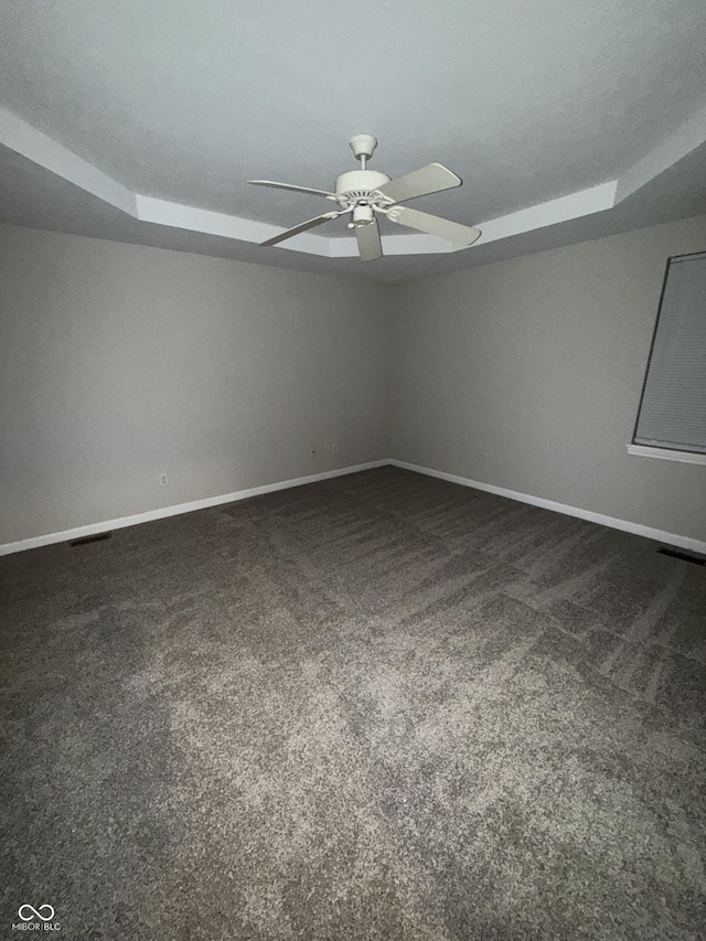 unfurnished room with ceiling fan and dark colored carpet