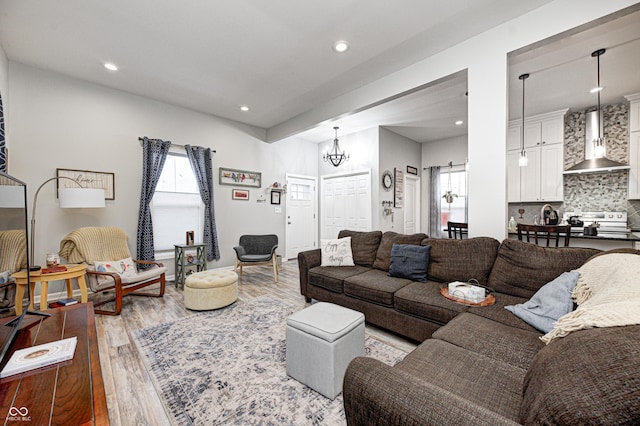 living room featuring an inviting chandelier, a barn door, and light hardwood / wood-style floors