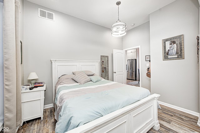 bedroom with hardwood / wood-style floors and stainless steel fridge