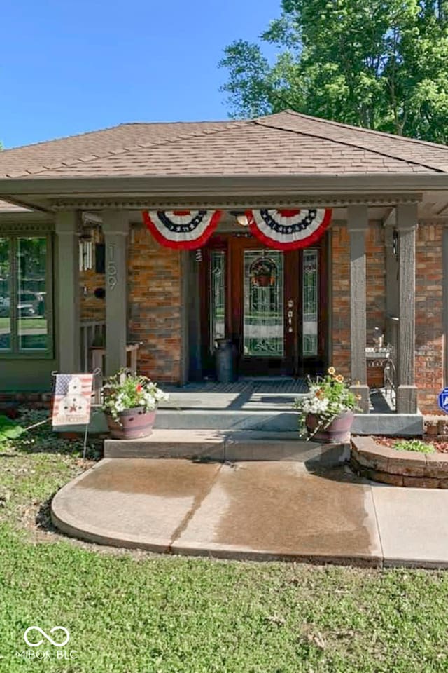 view of exterior entry with a lawn and a porch