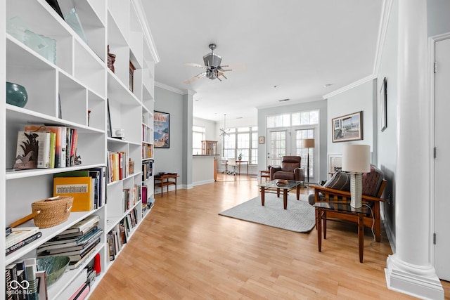 living area with decorative columns, crown molding, ceiling fan, and light hardwood / wood-style floors