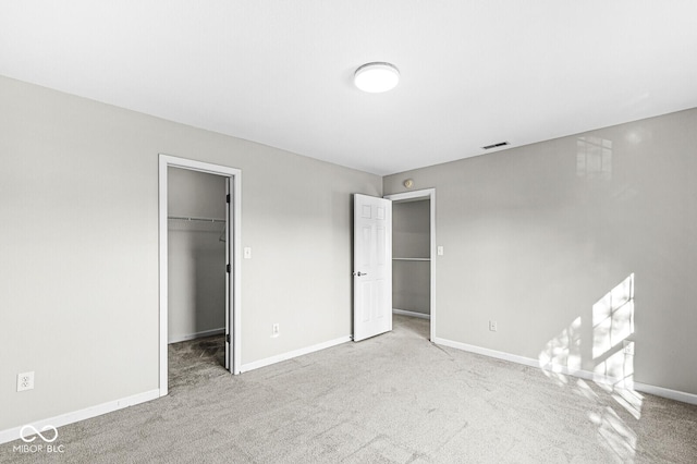 unfurnished bedroom featuring a closet, a spacious closet, and light carpet