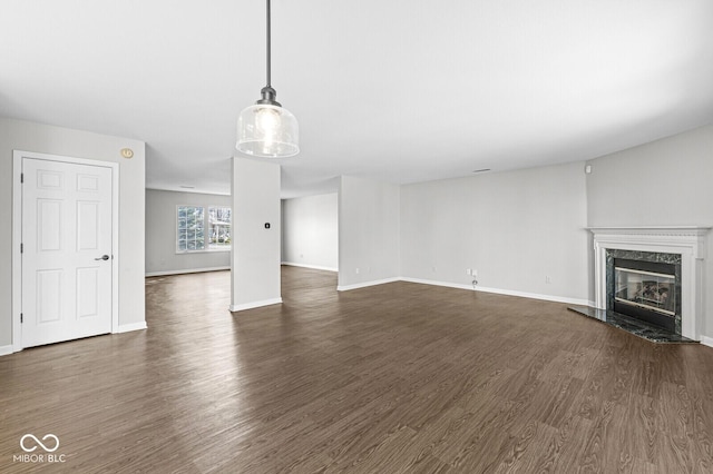 unfurnished living room featuring dark wood-type flooring and a high end fireplace