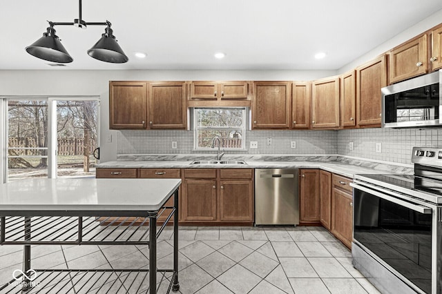 kitchen with appliances with stainless steel finishes, sink, pendant lighting, and backsplash