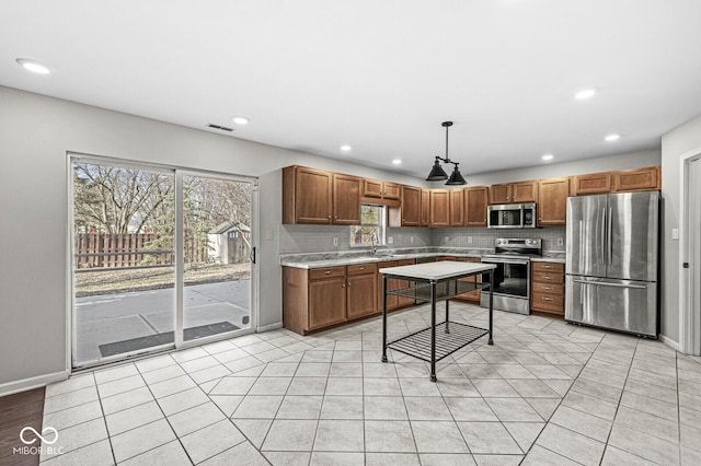 kitchen featuring appliances with stainless steel finishes, a wealth of natural light, hanging light fixtures, and backsplash