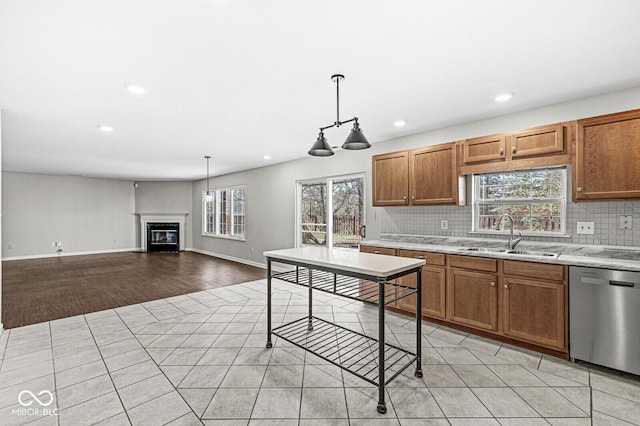 kitchen featuring sink, light tile patterned floors, stainless steel dishwasher, pendant lighting, and backsplash