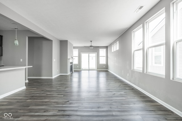 unfurnished living room featuring dark wood-type flooring and ceiling fan