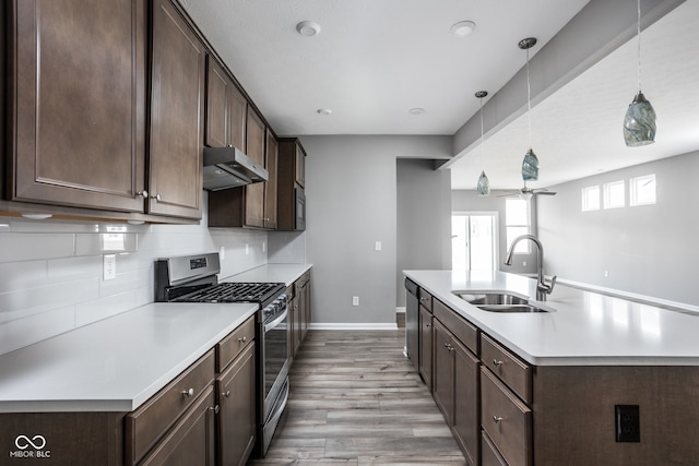 kitchen with pendant lighting, sink, backsplash, dark brown cabinetry, and stainless steel appliances