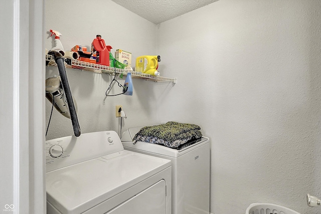 laundry area with separate washer and dryer and a textured ceiling