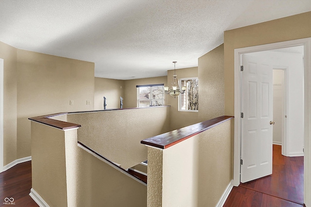 hallway featuring a chandelier, a textured ceiling, and dark hardwood / wood-style flooring