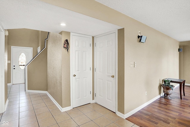 hallway with a textured ceiling and light hardwood / wood-style flooring