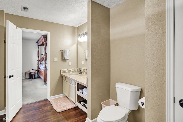 bathroom featuring wood-type flooring, vanity, a textured ceiling, and toilet